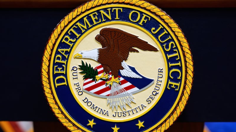 FILE - The U.S. Department of Justice logo is seen on a podium before a press conference, May...
